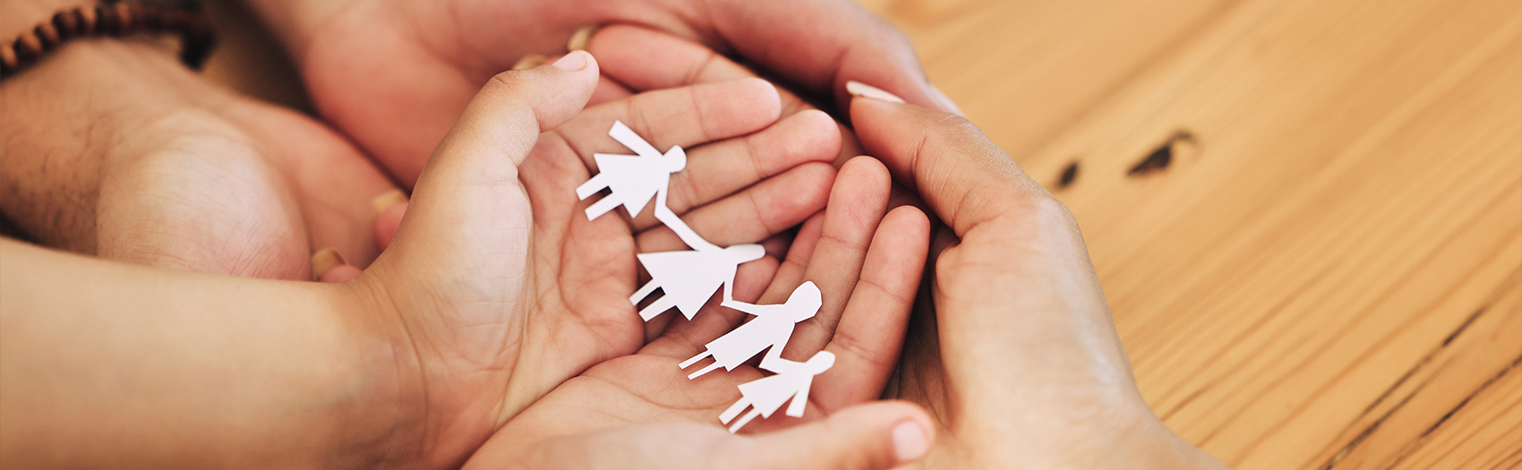 Hands holding paper cut-out family figures.