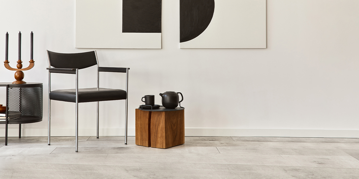 Minimalist interior with a black chair and wooden cube table.